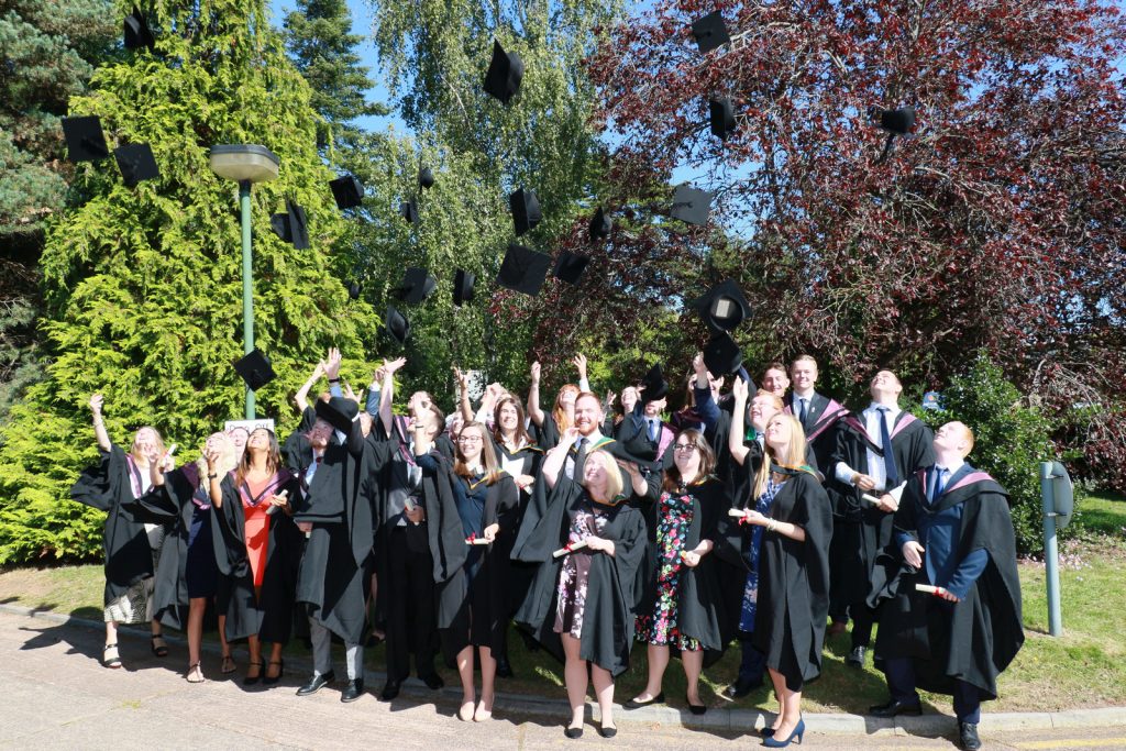 Graduates enjoying sunshine and throwing mortar boards